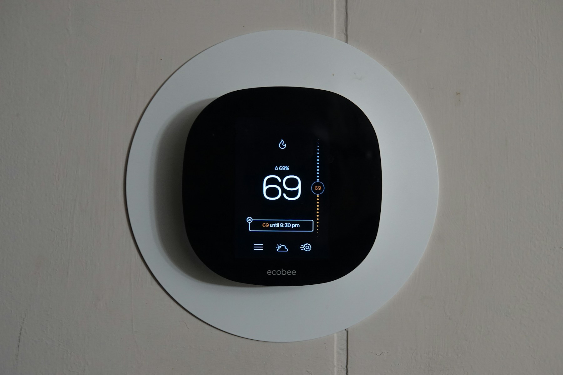 Wall-mounted thermostat displaying the home temperature